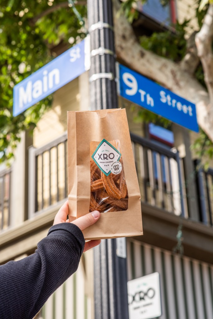 Fresh XRO churros in a branded paper bag