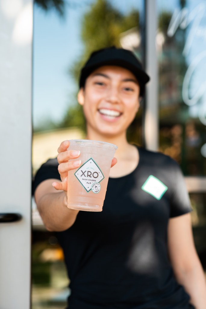 An XRO team member welcoming a guest with an iced drink